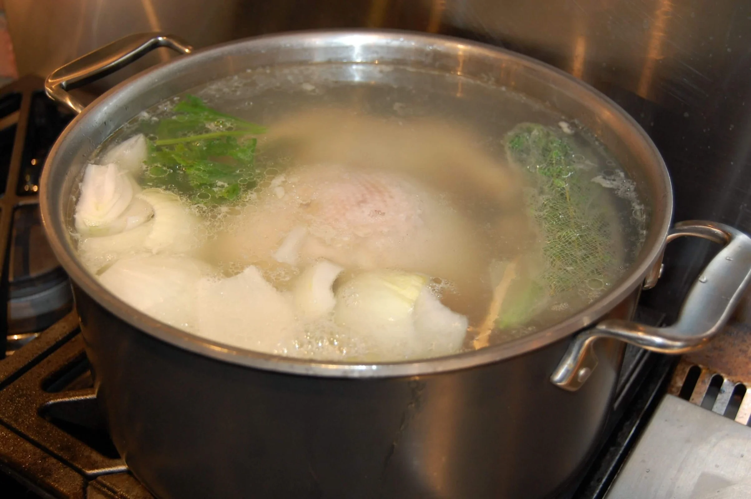 Chicken stock cooking in the pot on stove